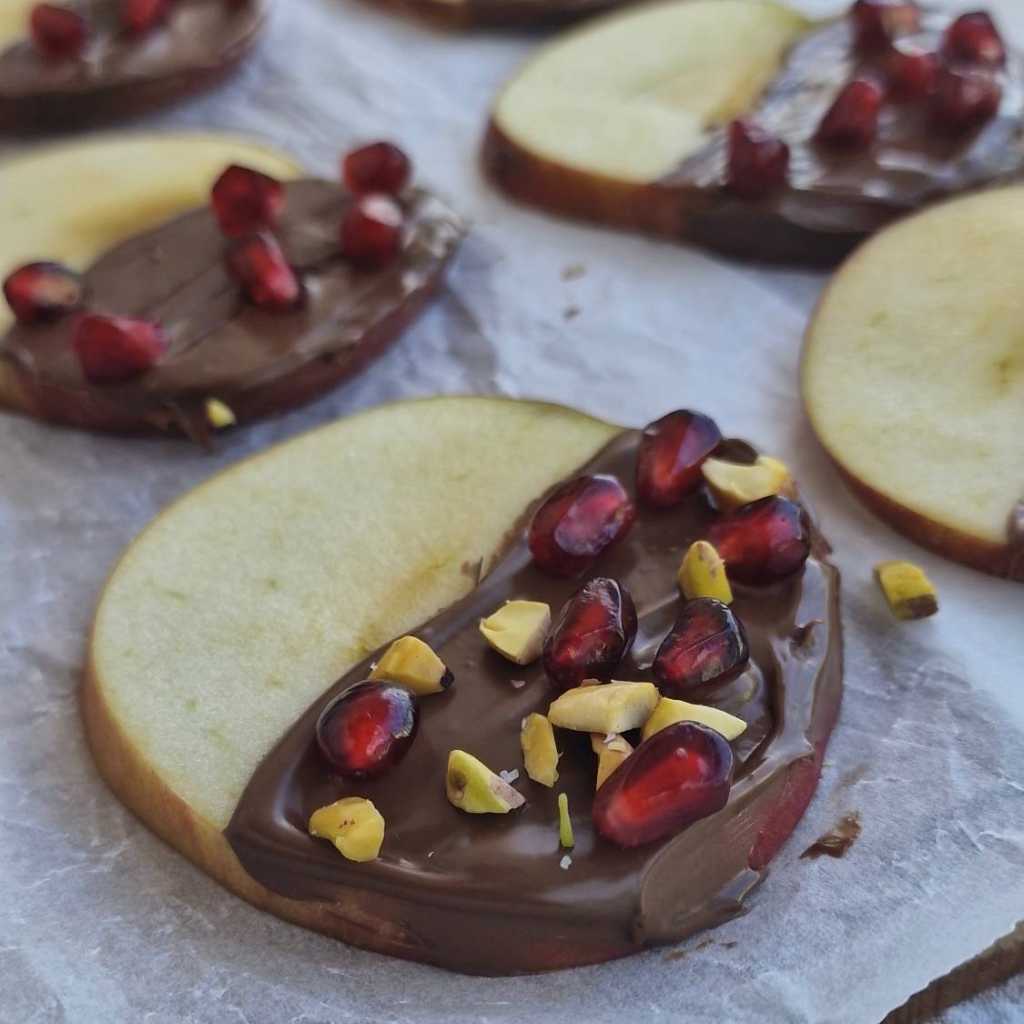 apple slices with chocolate and pomegranate and pistachio nuts