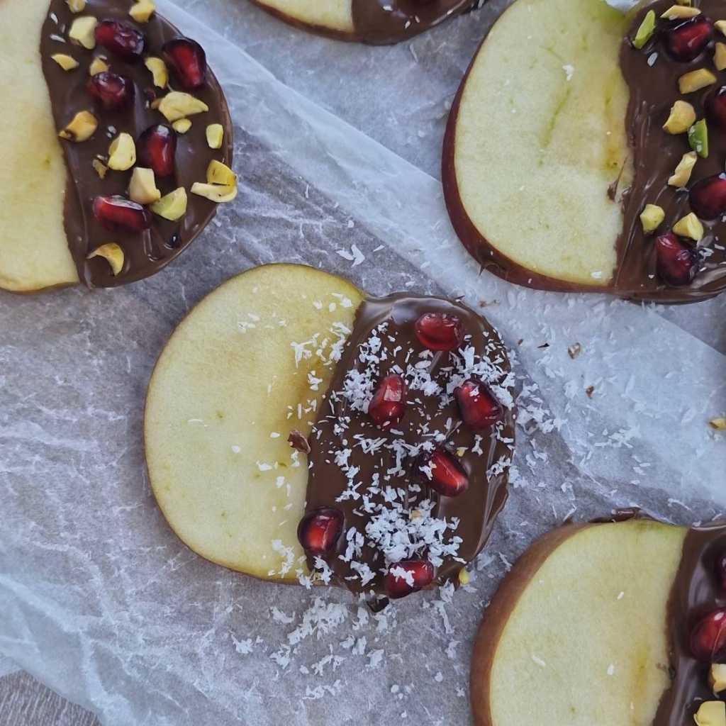 apple slices with chocolate and pomegranate and coconut flakes