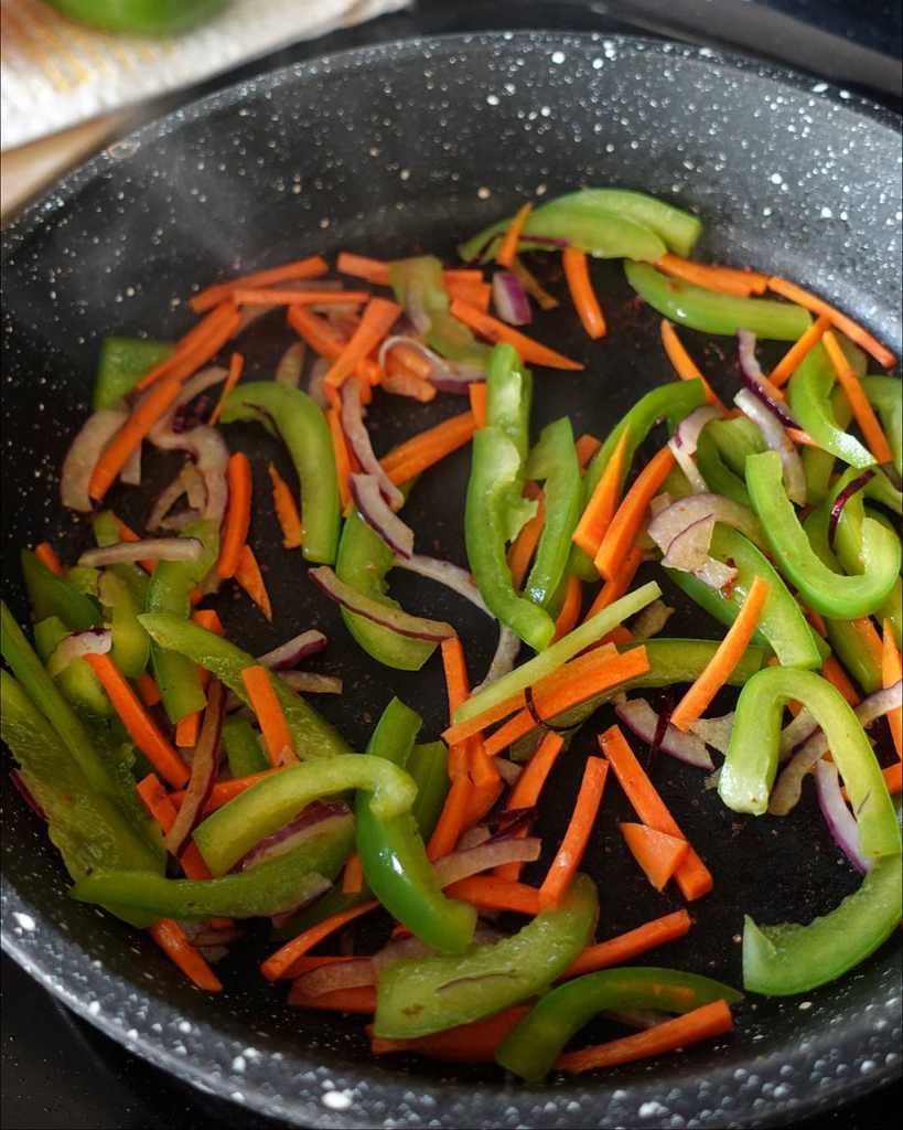 stir-frying red onion, carrots, bell pepper